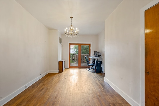 unfurnished office featuring hardwood / wood-style flooring, french doors, and an inviting chandelier