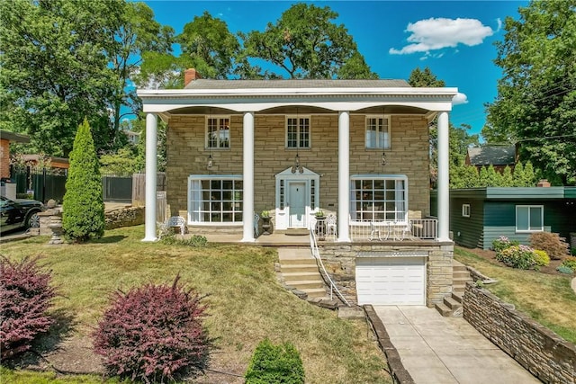 neoclassical / greek revival house featuring a garage, concrete driveway, stone siding, a front lawn, and a chimney