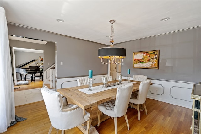 dining area with light hardwood / wood-style floors, crown molding, and a chandelier