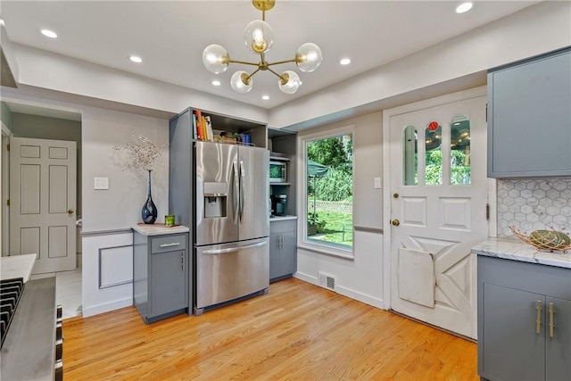 kitchen with stainless steel fridge, gray cabinets, pendant lighting, and light countertops