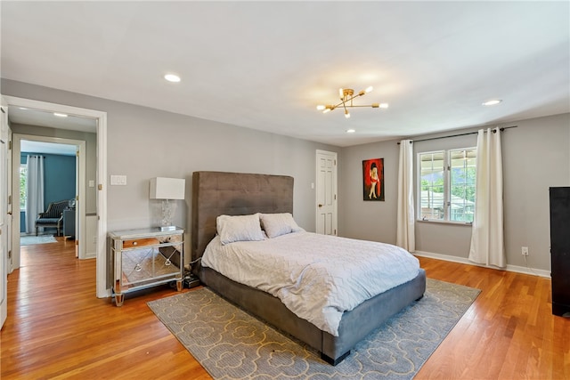 bedroom with light hardwood / wood-style flooring and an inviting chandelier