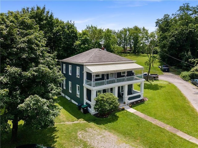 back of property with a yard and a balcony