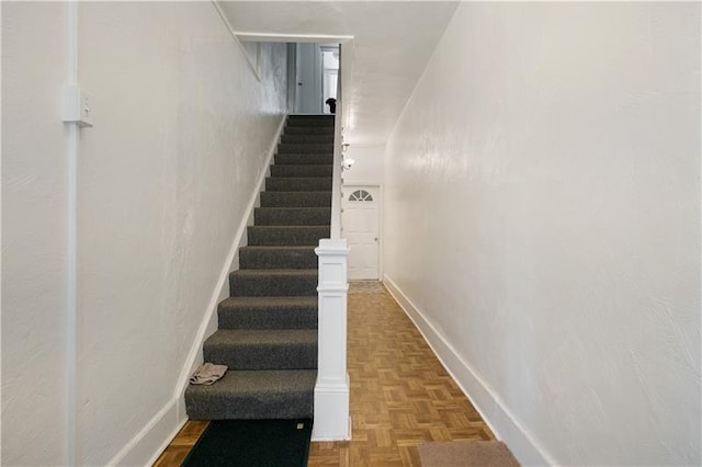 staircase featuring parquet flooring