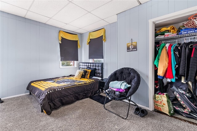 carpeted bedroom with a drop ceiling and a closet