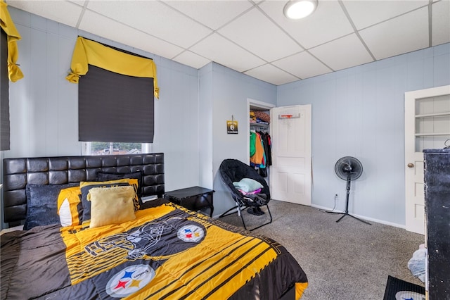 carpeted bedroom featuring a drop ceiling and a closet