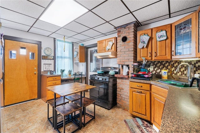 kitchen featuring light tile patterned flooring, decorative backsplash, black gas range, sink, and a paneled ceiling