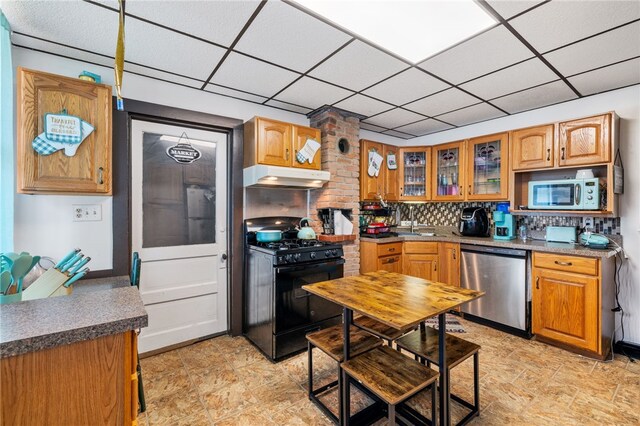 kitchen with tasteful backsplash, light tile patterned floors, stainless steel dishwasher, brick wall, and black gas stove