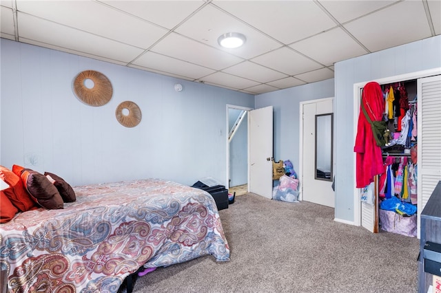 carpeted bedroom featuring a paneled ceiling and a closet