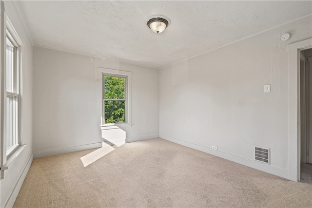 unfurnished room with a textured ceiling and light colored carpet