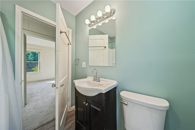 bathroom with hardwood / wood-style floors, vaulted ceiling, vanity, and toilet