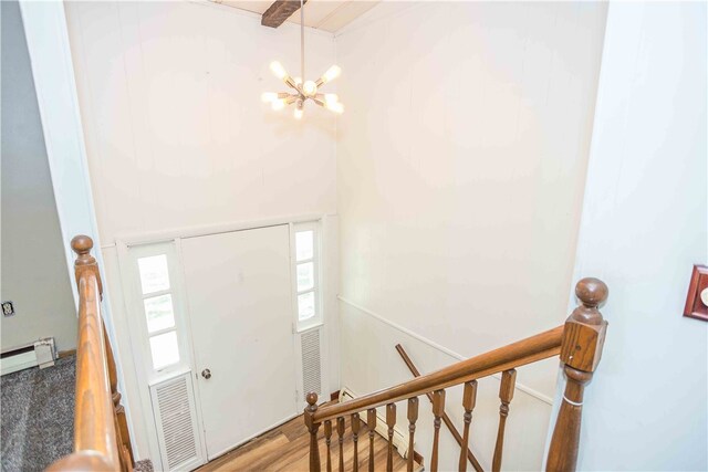 foyer featuring hardwood / wood-style floors, a baseboard heating unit, and a notable chandelier