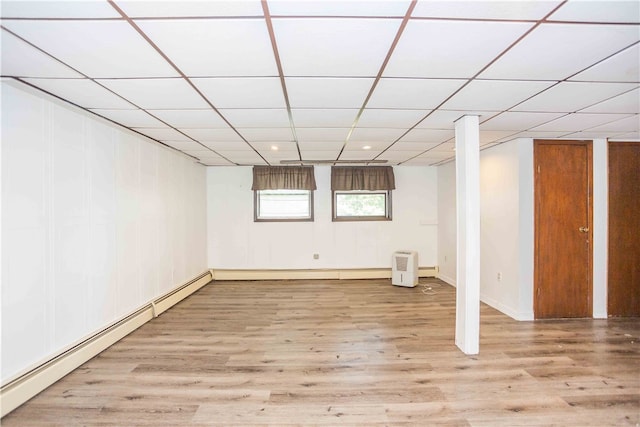 basement with a baseboard heating unit, wood-type flooring, and a drop ceiling