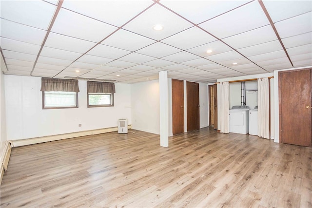 basement featuring separate washer and dryer, wood-type flooring, a baseboard heating unit, and a paneled ceiling