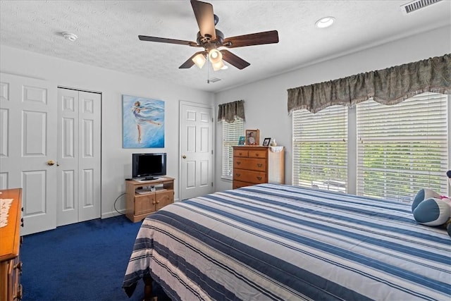 carpeted bedroom with ceiling fan, a closet, and a textured ceiling