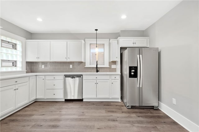 kitchen with hanging light fixtures, sink, light hardwood / wood-style floors, appliances with stainless steel finishes, and backsplash