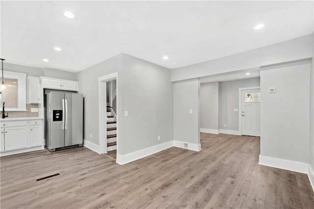 unfurnished living room featuring stairs, light wood-style flooring, recessed lighting, and baseboards