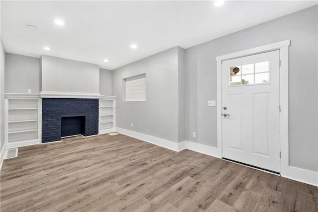 foyer featuring visible vents, a brick fireplace, baseboards, recessed lighting, and wood finished floors