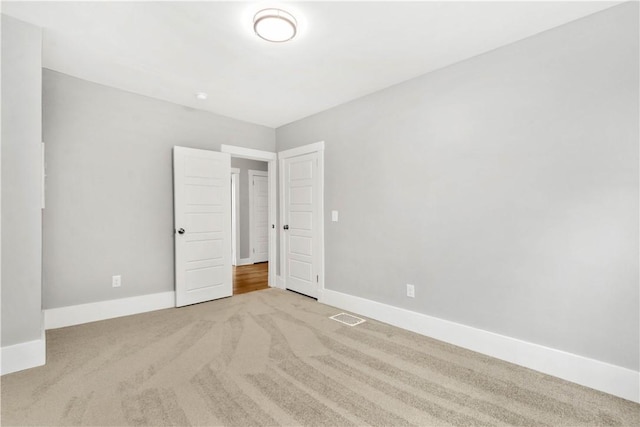 spare room featuring visible vents, baseboards, and light colored carpet