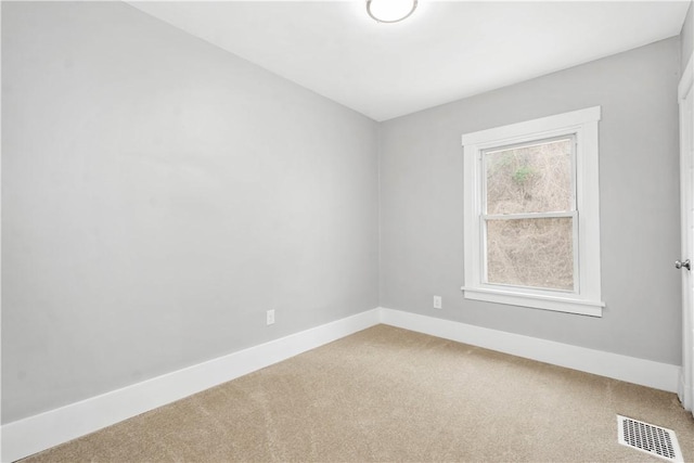 carpeted spare room with visible vents and baseboards