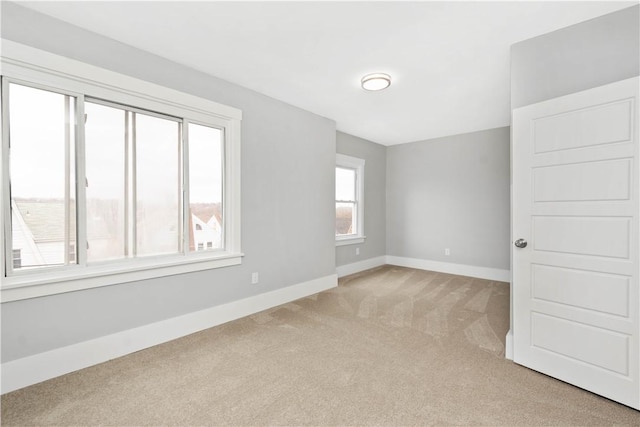 unfurnished room with light carpet and baseboards