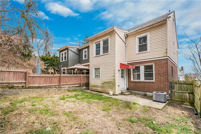 back of house with brick siding, entry steps, central AC, a fenced backyard, and a patio