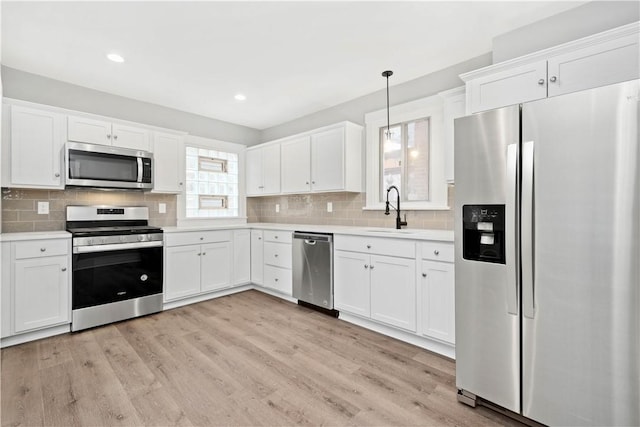 kitchen featuring a sink, stainless steel appliances, light countertops, white cabinetry, and light wood-type flooring