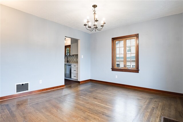 spare room with wood-type flooring and a chandelier