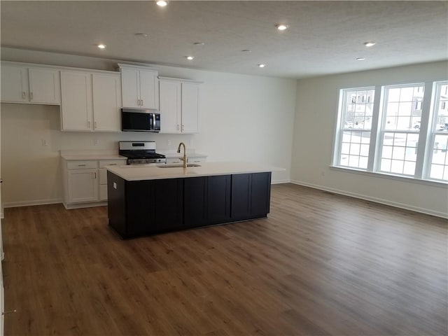 kitchen featuring stainless steel appliances, white cabinetry, a kitchen island with sink, and sink