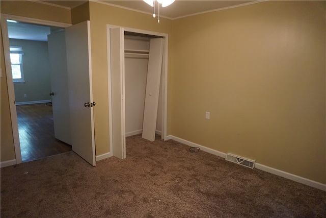 unfurnished bedroom featuring crown molding, dark hardwood / wood-style floors, and a closet