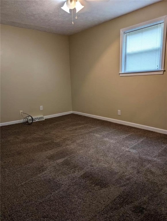 unfurnished room featuring ceiling fan, a textured ceiling, and dark colored carpet