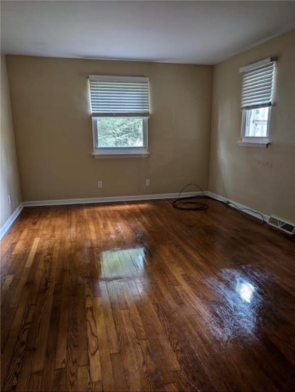 empty room featuring a healthy amount of sunlight and dark hardwood / wood-style floors