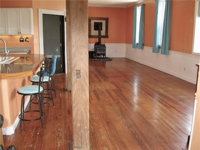 kitchen featuring white cabinetry, a wood stove, dark wood-type flooring, and a kitchen breakfast bar