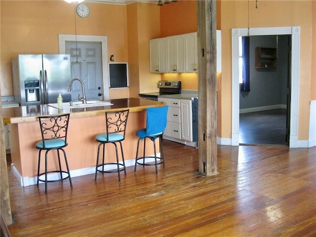 kitchen with appliances with stainless steel finishes, a center island with sink, white cabinets, and a kitchen breakfast bar