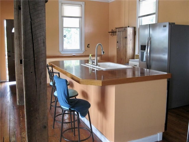 kitchen featuring an island with sink, sink, a breakfast bar area, dark hardwood / wood-style flooring, and stainless steel fridge with ice dispenser