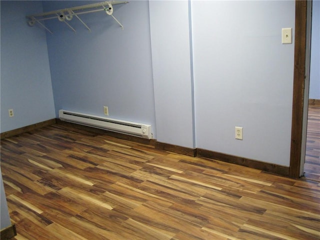 unfurnished bedroom with hardwood / wood-style flooring and a baseboard heating unit