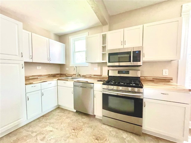 kitchen featuring white cabinetry, stainless steel appliances, butcher block counters, and sink