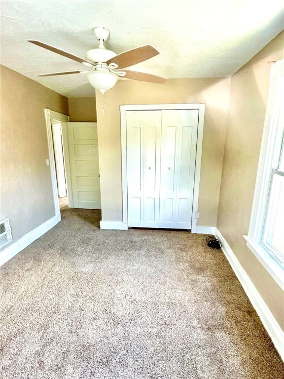 unfurnished bedroom with ceiling fan, a closet, and carpet floors