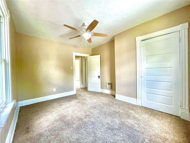 unfurnished bedroom featuring ceiling fan, a textured ceiling, and carpet