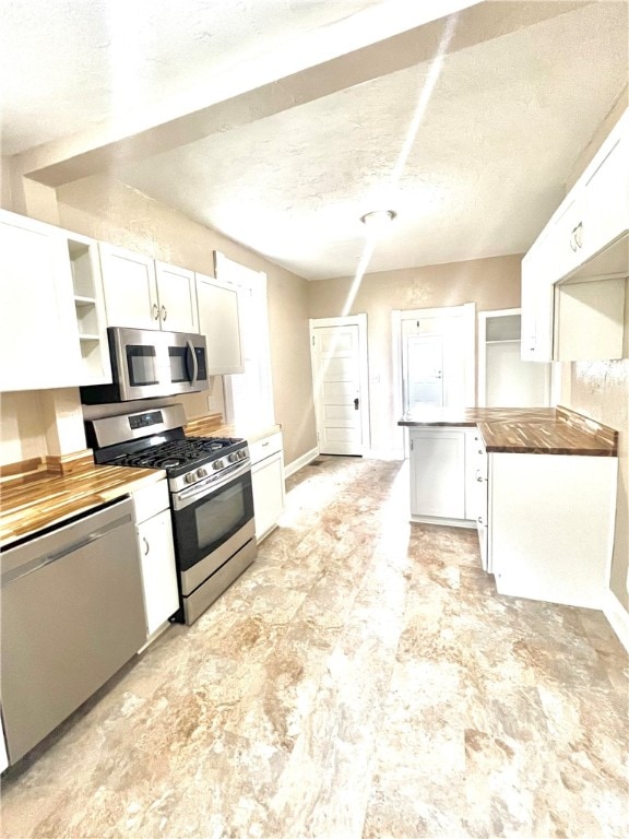 kitchen featuring wooden counters, white cabinetry, a textured ceiling, and appliances with stainless steel finishes