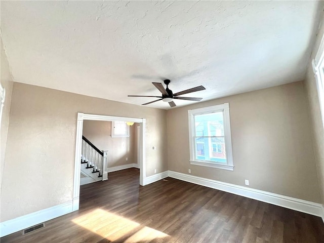 empty room featuring ceiling fan, dark wood-type flooring, and a textured ceiling