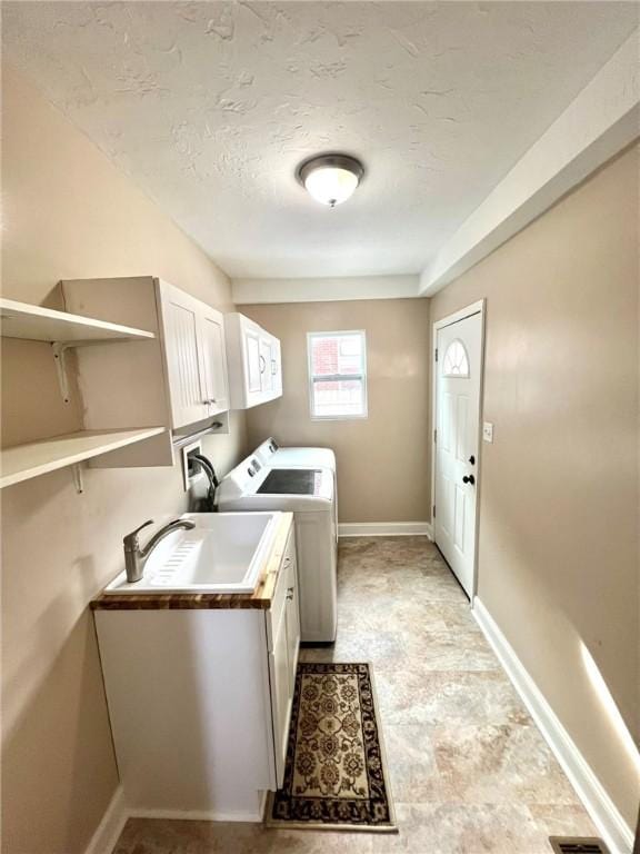 laundry area featuring washer and dryer, sink, cabinets, and a textured ceiling