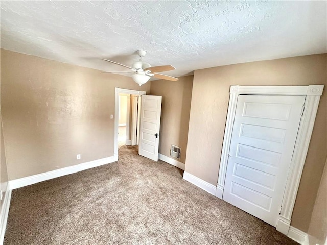 unfurnished bedroom with ceiling fan, carpet floors, and a textured ceiling