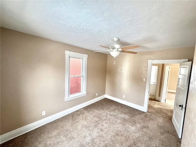 carpeted empty room with ceiling fan and a textured ceiling