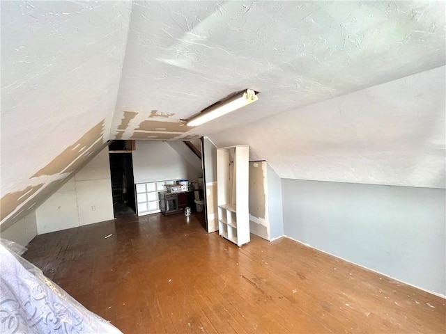 bonus room featuring wood-type flooring, a textured ceiling, and vaulted ceiling