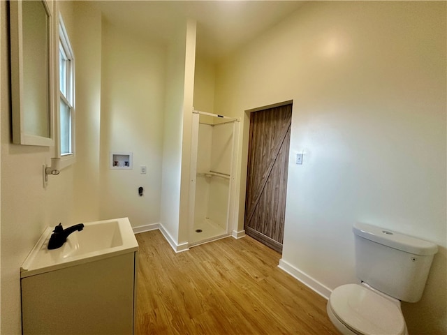 bathroom with a shower, wood-type flooring, vanity, and toilet