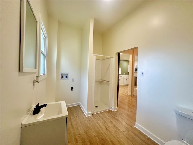 bathroom with toilet, vanity, hardwood / wood-style flooring, and a shower