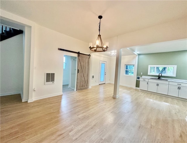 unfurnished dining area with light hardwood / wood-style flooring, a barn door, and sink