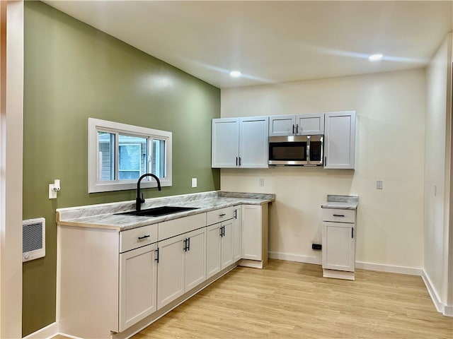 kitchen featuring light wood-type flooring, sink, and white cabinetry