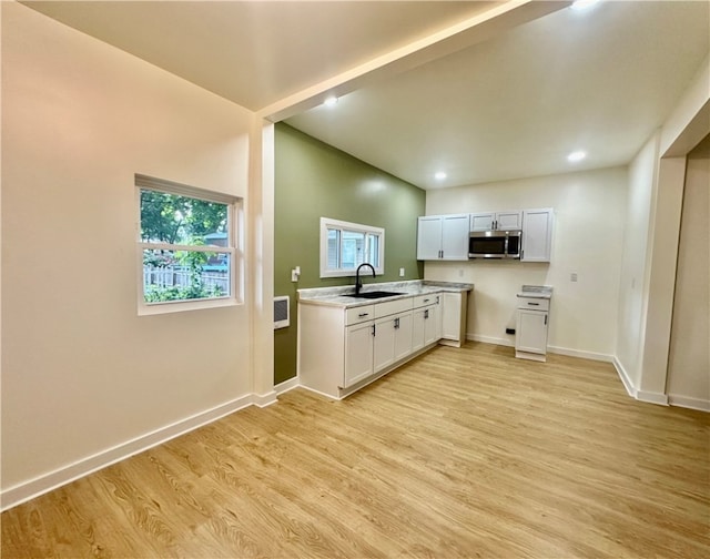 kitchen featuring light hardwood / wood-style flooring, sink, vaulted ceiling, and white cabinetry