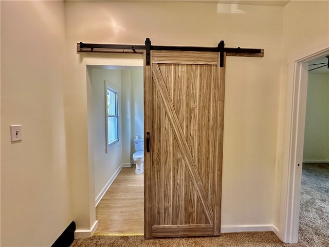 hall with light carpet and a barn door